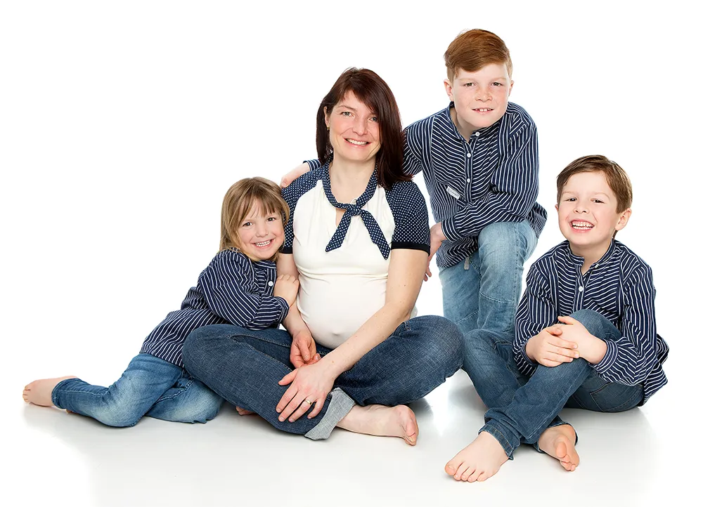 Familienfoto einer Mutter mit drei Kindern – möglicherweise schwanger – sitzend auf weißem Hintergrund im Fotostudio Foto Ape in Rostock